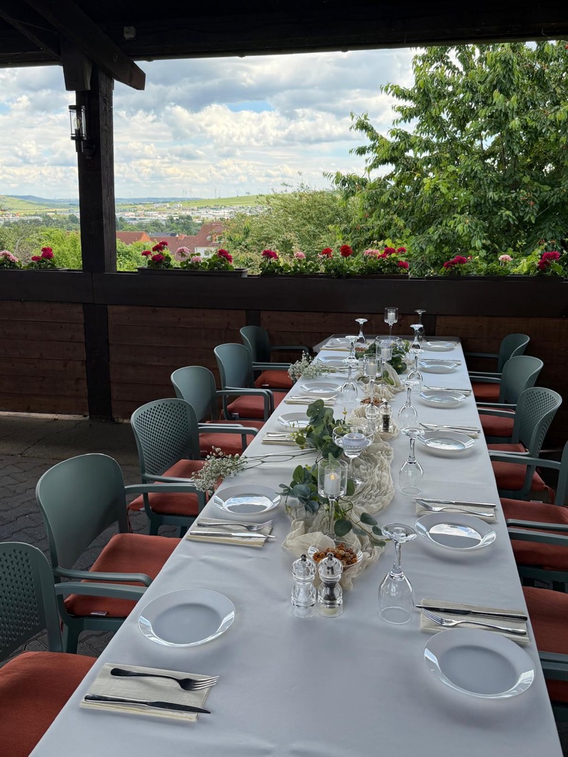 Festlich eingedeckte lange Tafel auf der Terrasse mit Blick ins Tal