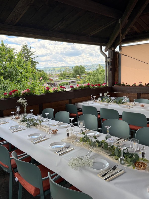 Weiß gedeckte Tafel mit Blumenschmuck und Geranien